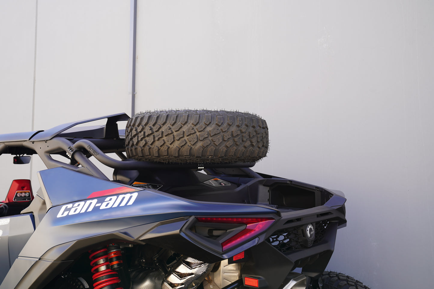 Can-Am vehicle with a spare tire mounted on the back against a white wall