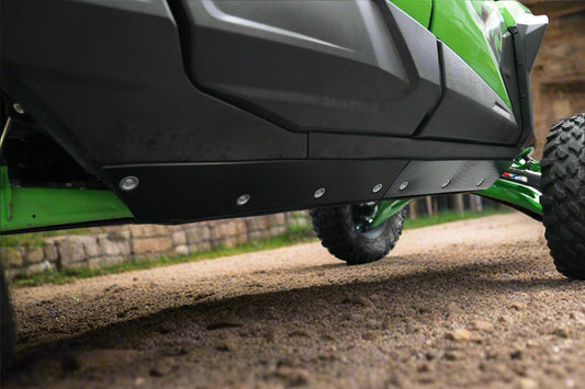 Close-up of a green vehicle's undercarriage with a black protective cover in a garage setting.
