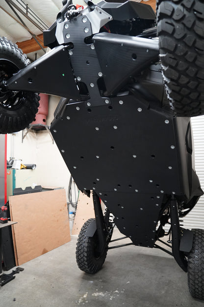Factory UTV skid plate installation taking place in workshop with vehicle on lift.